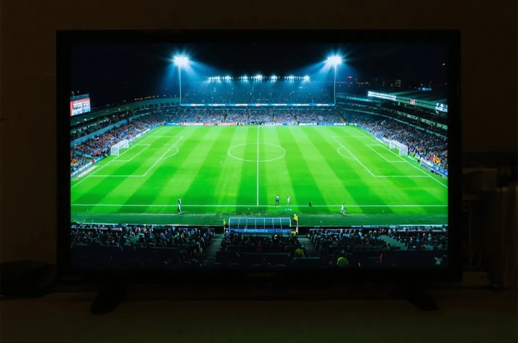 A high-definition television screen displaying a vibrant green soccer field during a professional match